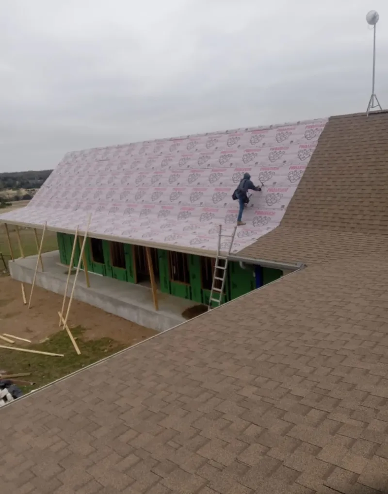 Worker preparing underlayment for a metal roof installation in Concord